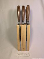 Front view showing three knives in wooden block with visible bee emblems on bolster ends.