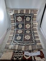 Full view of Polynesian tapa cloth inside plastic wrapping showing design and size