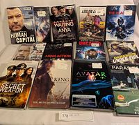 Photo showing 11 sealed DVDs arranged in rows including Avatar, Parasite, Logan 4, The King, Waiting For Anya, Human Capital, and more.