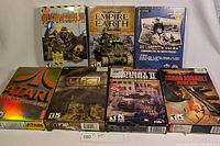 Photo showing full lot of seven original PC game boxes arranged in two rows on white surface.