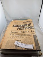 Photo showing folded vintage Boston Evening Globe newspaper with headline 'Arraignment Postponed'.