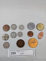 13 vintage world coins and tokens arranged in rows on a white background, showing front sides with various designs and materials.