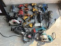 Variety of corded and cordless drills, circular saw, grinders, chargers on concrete floor