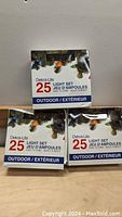 Photo of three boxed Dekra-Lite 25 light sets for outdoor use, arranged stacked with one on top and two below, showing front packaging.