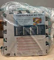 Plastic packaging containing foam puzzle play mat pieces with label showing product features and item numbers.