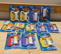 Photo showing 12 kite handlers in packaging with assorted colors placed on wooden surface