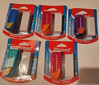 Photo showing five new Maped retractable erasers in assorted colors, each in original packaging with one eraser and one refill.