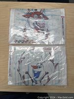 Two Olaf 5D diamond painting kits sealed in plastic, displayed on a wooden surface. Both kits show pixelated Olaf designs printed on canvas for diamond dot application.