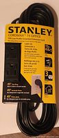 Photo of new Stanley Cordmax 15 Office 15 foot low profile grounded extension cord on original packaging, showing 3 grounded outlets and 45° flat plug.