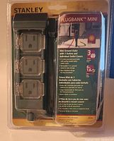 Front view of Stanley Plugbank Mini in original packaging showing 3 grounded outlets with safety covers and ground stake.