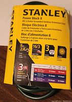 Yellow Stanley Power Block 3-Outlet 8ft grounded outdoor extension cord packaging showing product details including cable gauge 16/3 AWG, number of outlets, length, and outdoor rating.