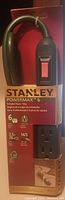 Front view of Stanley Powermax 6 outlet power strip in original packaging showing outlets, on/off switch, cable and brand details.