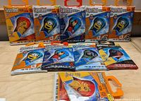 Photo of all ten Supersled nylon frameless kites in original packaging with various popular character designs including Minions, Spider-Man, Captain America, and Lion King.