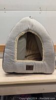 Front view of the triangular-shaped Windracing indoor cat bed showing the arched entrance and plush interior.