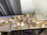 Photo showing spread of various world paper currency bills arranged on a table including visibly crumpled and taped notes.