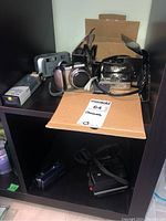 Shelf with various cameras and boxes showing multiple cameras and accessories