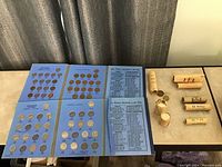 Overview of blue fold-out cardboard coin sleeves and five paper coin rolls on tabletop