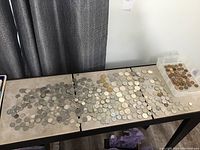 Overview of approximately 150 coins spread across a table
