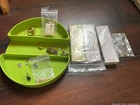 Overview of green compartment tray with multiple jewelry items and sealed boxes