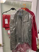 Three hanging leather items: a folded red leather skirt, a grey jacket in dry cleaner plastic, and a faded red leather jacket.
