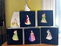 Seven miniature Royal Doulton figurines in original boxes with one displayed outside showing details and scale.