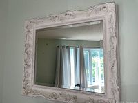 Full view of rectangular mirror showing white ornate carved frame with floral and scroll motifs.