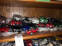 Wide view of wooden shelves filled with multiple model cars in bubble wrap.