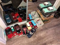 Floor overview with multiple loose and boxed die-cast cars and two mint green models on display stands