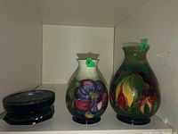 Two vases and one dish on shelf with green lot tags (#6 on small vase, #7 on large vase)