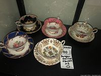 All five Paragon teacup and saucer sets displayed on black shelf