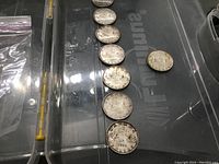 Eight coins arranged on plastic surface showing seven 1963 and one 1953 coin