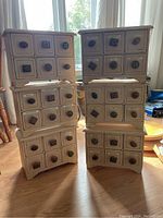 Six stacked wood organizers with six drawers each, white distressed finish with decorative ceramic knob handles.