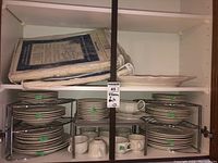 Full cabinet view with multiple stacks of plates, bowls, cups and packing covers on top shelf