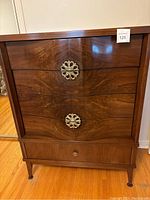 Front view of Princeville Art Deco bedroom chest of drawers highlighting the curved drawers and ornate brass pulls.