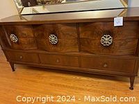 Front view of the dresser showing six drawers with decorative metal handles and wood finish.