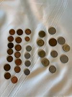 Top-down view of a group of 29 coins in various sizes and metal colors arranged loosely in rows