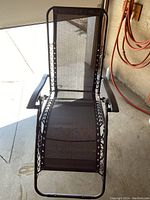 Front view of black gravity chair showing mesh seat and backrest, arm rests, and reclining frame.