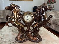 Front view of ceramic twin horse clock showing two rearing horses and clock face