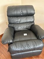 Front view of black leather recliner showing padded seat, back, and armrests with leather upholstery.