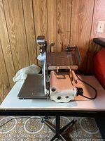 Side view of vintage Berkel meat slicer on table showing the slicer's body, handle, and power cord.