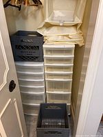 Closet with two plastic drawer carts (6 and 7 drawers), two black plastic milk crates, fabric shoe racks stacked on top of drawer carts, assorted wooden and plastic clothing hangers on rod, and pink metal shoe racks above.