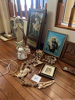 Photo showing most items including statues, framed art, rosary, and smaller figurines arranged on wooden floor