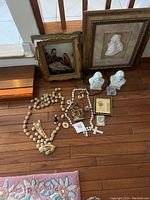 Photo showing all religious items including framed prints, rosaries, statues, and crosses arranged on the floor.