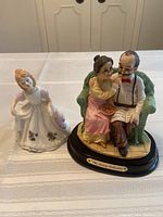 Two porcelain figurines on table: Royal Doulton February girl and elderly couple from Natelia Collection