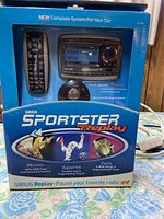 Front view of the sealed box showing Sirius Sportster Replay receiver with remote control and branding.