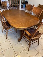 Photo of entire oak dining table with four side chairs and two armchairs, all in matching oak wood with cushions.
