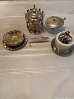 Overview of all items in the lot including sugar bowls, spoons, napkin holder.
