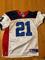 Front view of white football jersey with navy blue and red detail, front number 21 and team branding patches.