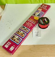 Photo of the boxed Deluxe E-Z Bow Maker and pink ribbon spool on table with auction lot tag visible.