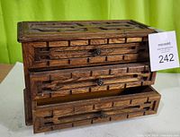 Front view of wooden jewelry box with carved geometric design and both drawers open